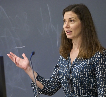 Woman in dress in front of a classroom blackboard